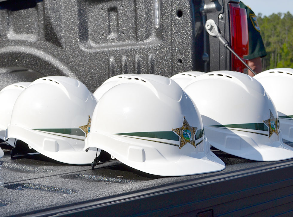 Picture of the hard hats with the decals on them sitting on a truck tail gate